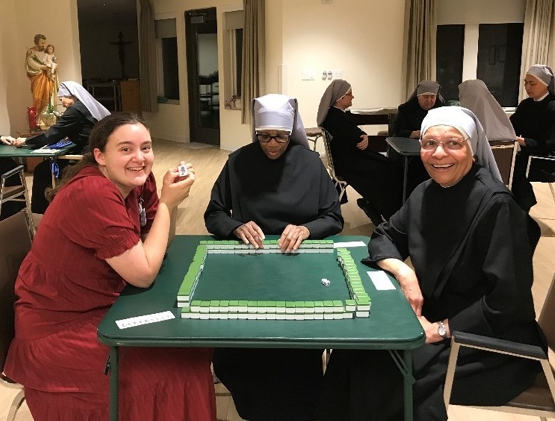 young girl sitting at table with two little sisters playing mahjong