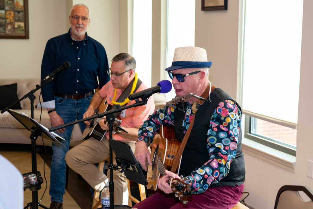 two men play guitars while one man looks on